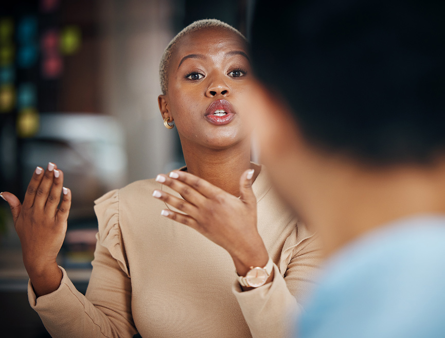 A young Black woman with short, blonde hair speaks passionately, gesturing with her hands.